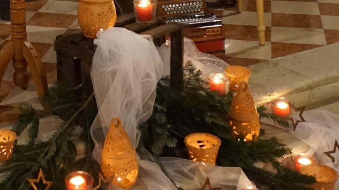 Eine festliche Dekoration mit Kerzen und Laternen auf einem Holztisch. Grüne Zweige und Sterne ergänzen die stimmungsvolle Atmosphäre. | © Trachenverband Mürztal