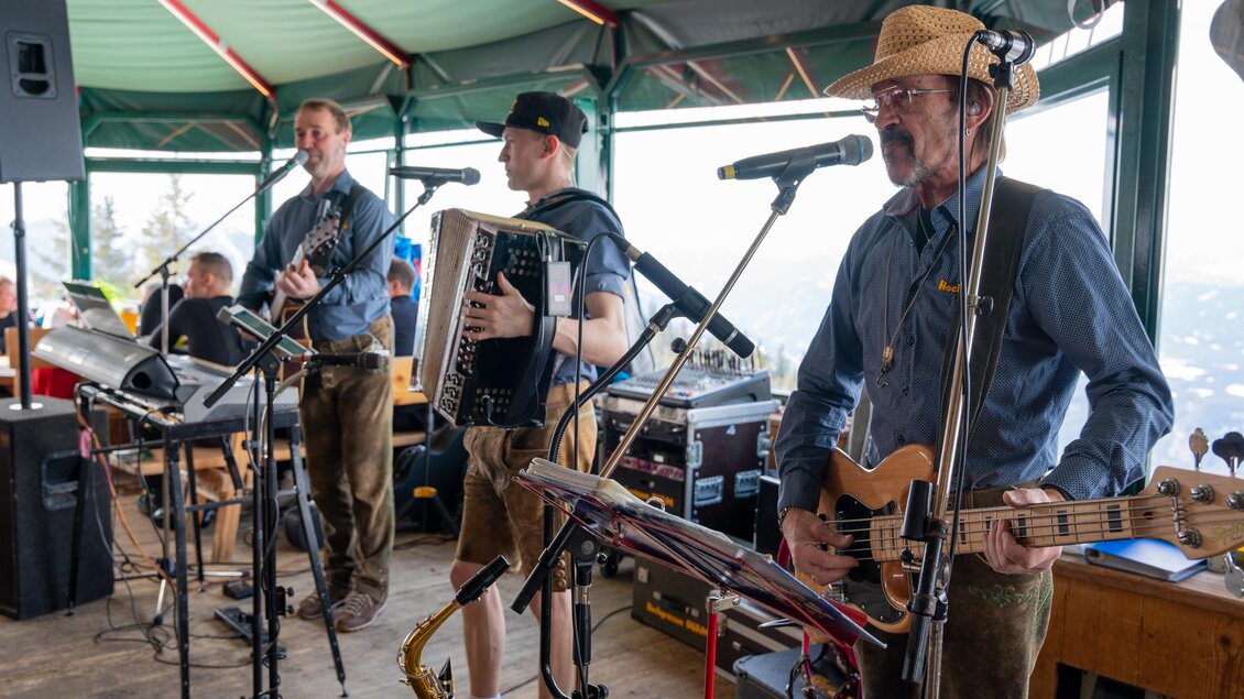 Drei Musiker in Trachten spielen in einem Bergrestaurant. Sie verwenden verschiedene Instrumente und unterhalten die Gäste mit Live-Musik. | © Mario Egger
