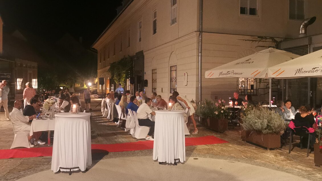 Eine elegante Abendveranstaltung mit Gästen an Stehtischen. Die Szenerie ist festlich geschmückt und beleuchtet. | © CDM incoming - Fotostudio Augenblick