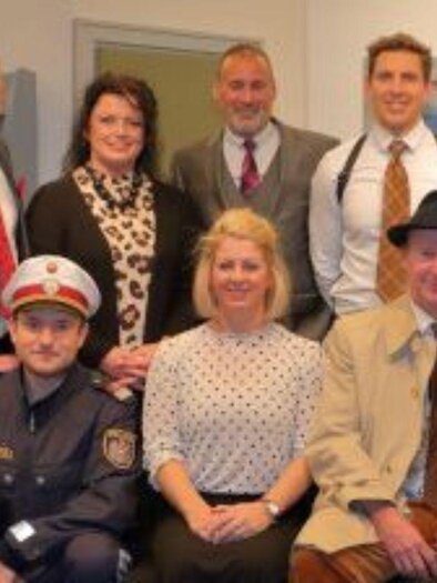 A group of people is posing indoors. Some are wearing formal clothing while others are in uniforms. | © Knoschpnbühne 2024(c) Ausseer Knoschpnbühne