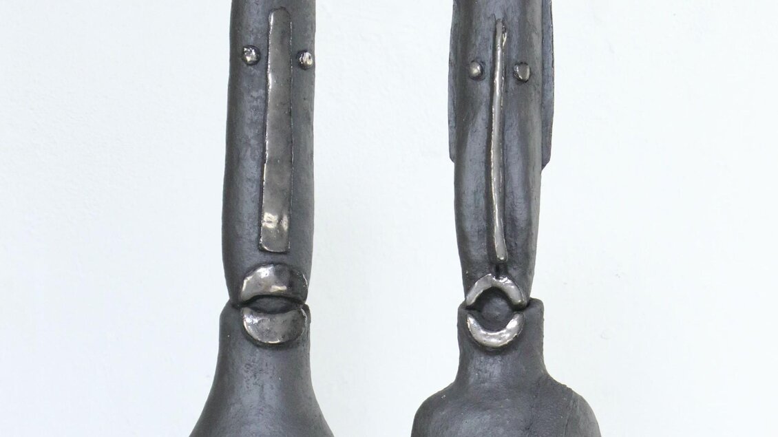 Zwei abstrakte, dunkle Tonskulpturen mit länglichen Köpfen, Teil der Ausstellung „Zeitreisende“ im Kunsthaus Köflach | © Agathon Koren