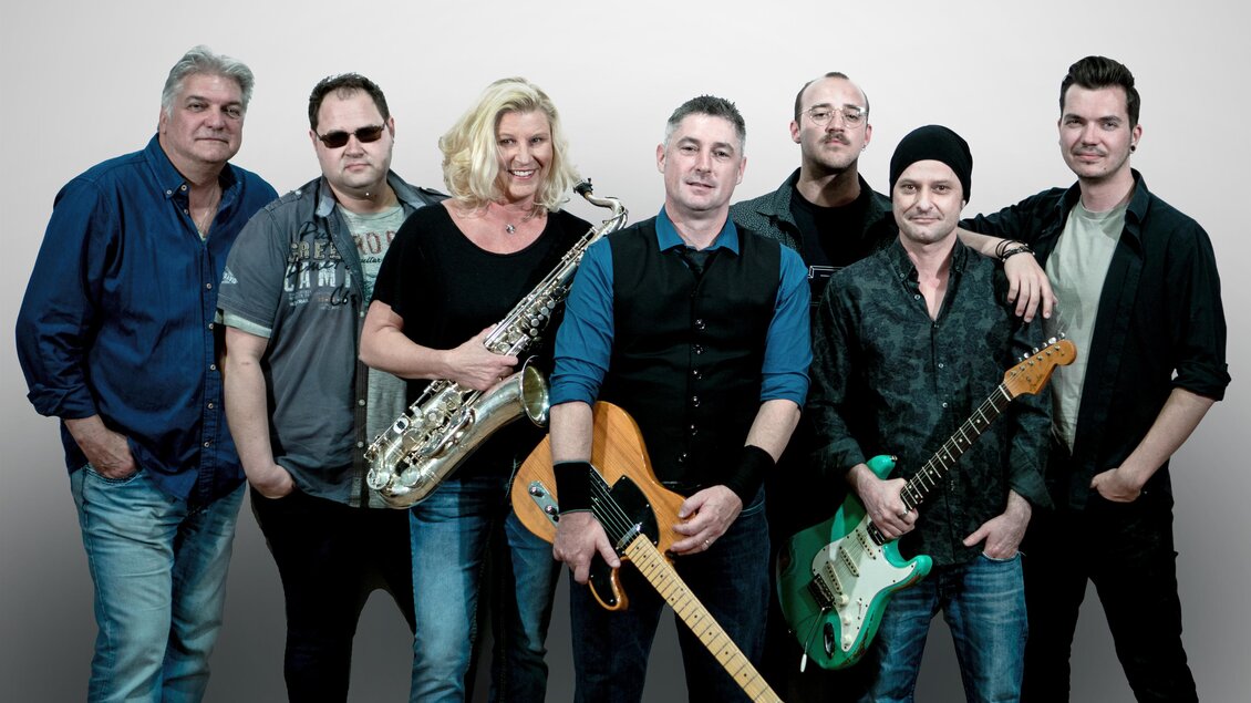 Eine Band steht zusammen und posiert für das Foto. Sie haben verschiedene Instrumente und zeigen eine freundliche Atmosphäre. | © BOSStria