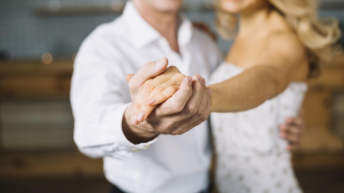 Ein Paar tanzt eng umschlungen. Sie halten sich an den Händen und lächeln glücklich. | © freepik