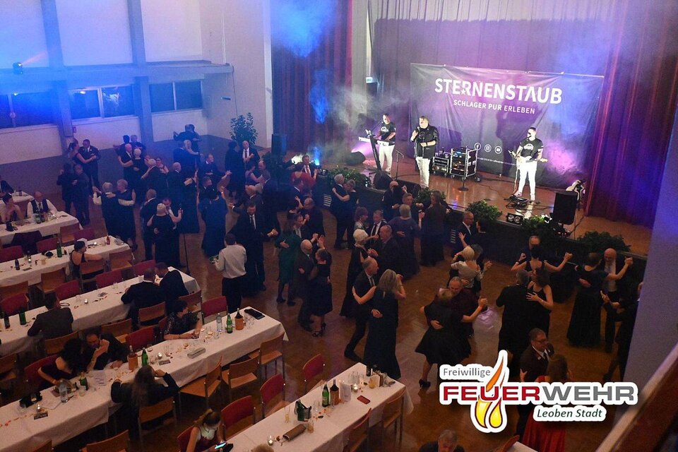 Eine festliche Veranstaltung mit tanzenden Gästen in formeller Kleidung. Im Hintergrund spielt eine Band auf einer Bühne mit bunten Lichtern. | ©  FF Leoben-Stadt