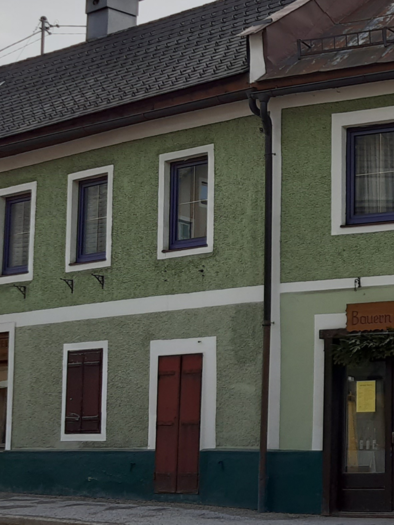 A green, two-story building with several windows. The entrance door is adorned and indicates that a restaurant is open. | © Daniela Casari