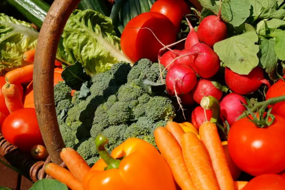 Ein Bauernmarkt mit frischem Obst und Gemüse. Im Vordergrund sind Äpfel und frisches Grün zu sehen. | © KK
