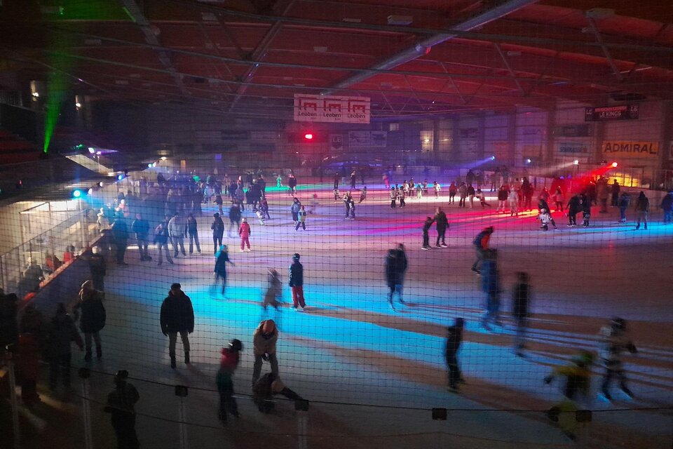 Eine belebte Eishalle mit vielen Menschen, die auf dem Eis schlittschuhlaufen. Farbige Lichter schaffen eine festliche Atmosphäre. | © Ralf Moder/ Facebook