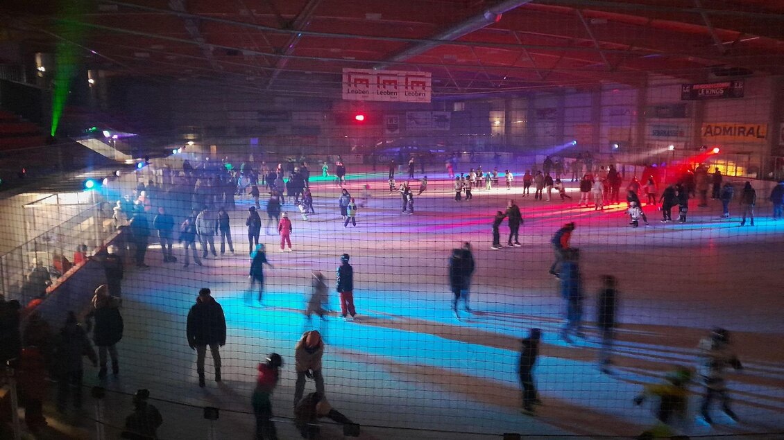 Eine belebte Eishalle mit vielen Menschen, die auf dem Eis schlittschuhlaufen. Farbige Lichter schaffen eine festliche Atmosphäre. | © Ralf Moder/ Facebook