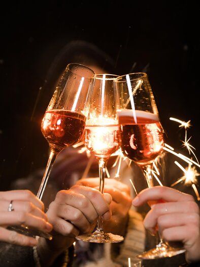 A festive gathering with champagne glasses being clinked. In the background, sparklers are glowing, creating a celebratory atmosphere. | © Lupi Spuma