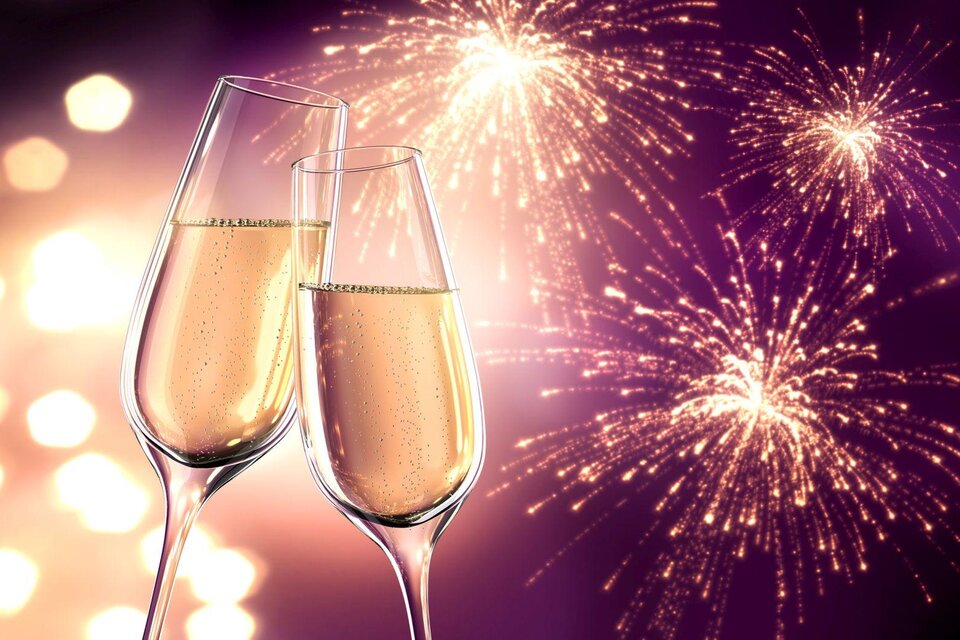 Zwei Sektgläser stoßen auf einen festlichen Anlass an, umgeben von bunten Feuerwerken. Der Hintergrund ist mit weichen Lichtern geschmückt und strahlt Freude aus. | © Fotalia