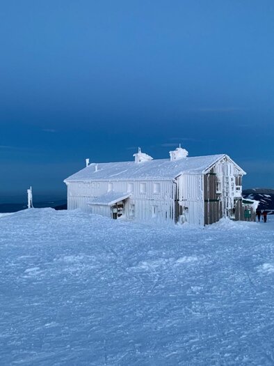 Ein weißes Gebäude steht in einer schneebedeckten Landschaft unter einem klaren, blauen Himmel. Die Umgebung ist ruhig und winterlich. | © Martin Ziegerhofer