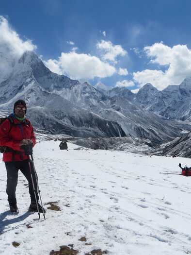 A hiker stands in the snow before majestic mountain peaks. The sky is clear and sunny with a few clouds. | © Kager Eduard