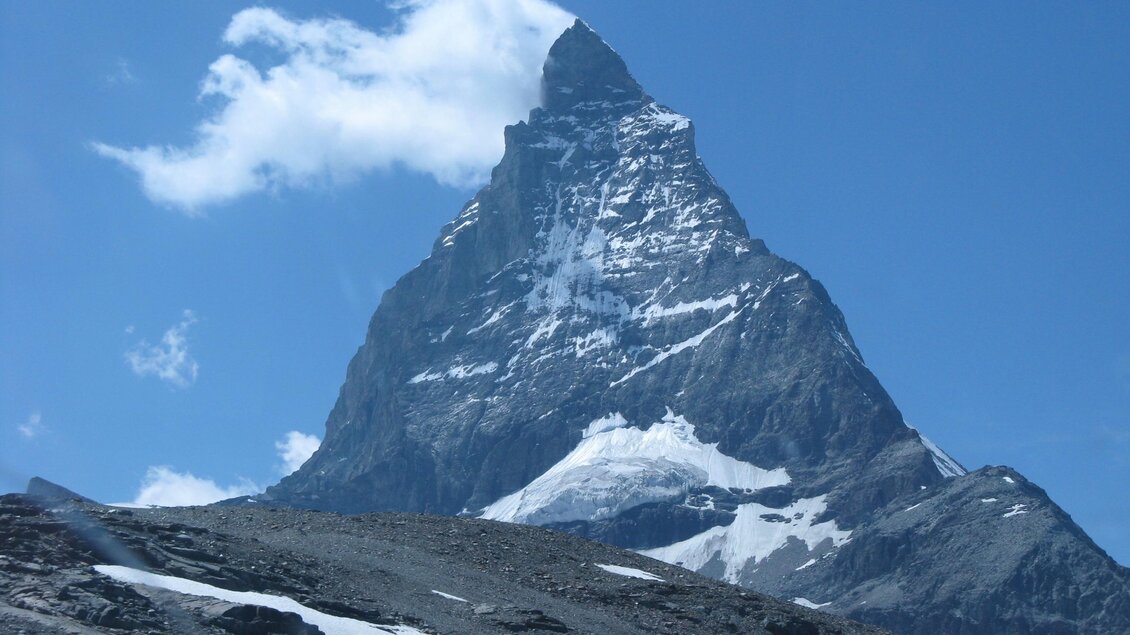 Ein majestätischer Berggipfel unter einem klaren blauen Himmel. Die Spitzen sind schneebedeckt, und die Umgebung ist felsig. | © Kager Eduard