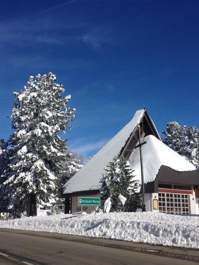 Eine verschneite Landschaft mit einem markanten Gebäude und hohen, schneebedeckten Bäumen. Der Himmel ist klar und blau. | © TV Turracher Höhe 