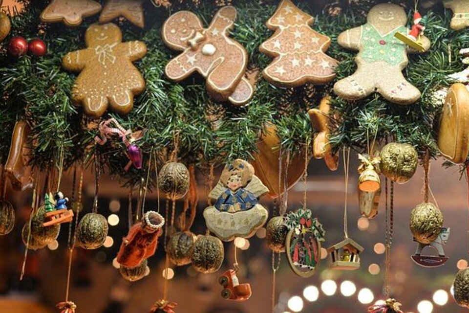 Ein festlicher Weihnachtsschmuck mit Lebkuchenmann-Figuren und bunten Ornamenten. Die Dekoration ist von grünen Tannenzweigen umgeben. | © Pixabay