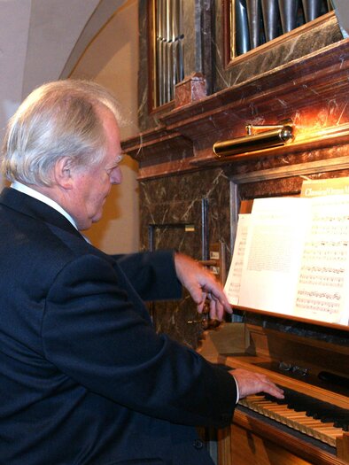 Ein Mann spielt an einer Orgel und schaut auf die Noten. Die Umgebung ist festlich und elegant. | © Sakralkunst Oststeiermark