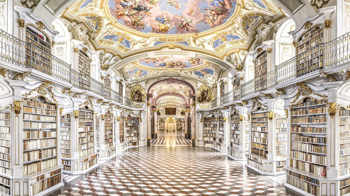 Eine prächtige Bibliothek mit hohen Decken und kunstvollen Fresken. Die Wände sind mit Regalen voller Bücher geschmückt. | © Stefan Leitner