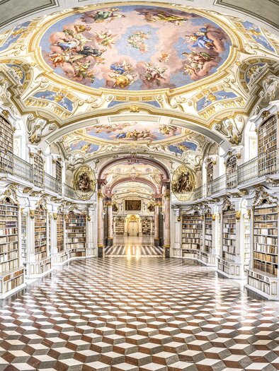 A magnificent library with high ceilings and intricate frescoes. The walls are adorned with shelves full of books. | © Stefan Leitner