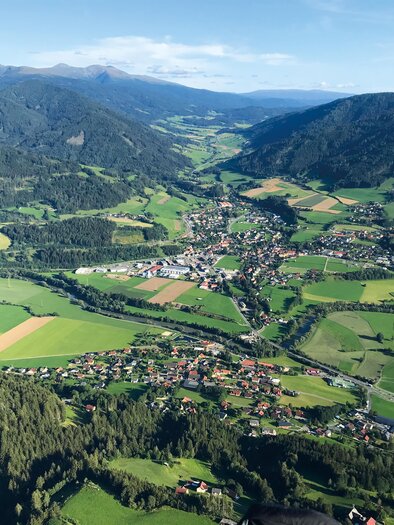 Ein weitläufiges Tal mit grünen Wiesen und Feldern ist zu sehen. Im Hintergrund erheben sich sanfte Berge unter einem klaren Himmel. | © TVB Murau