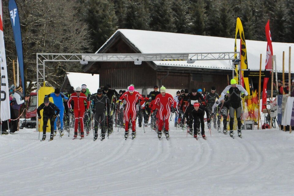 Eine Gruppe von Skifahrern startet ein Rennen auf einer Schneepiste. Im Hintergrund sind Bäume und ein Gebäude zu sehen. | © Georg Petritsch