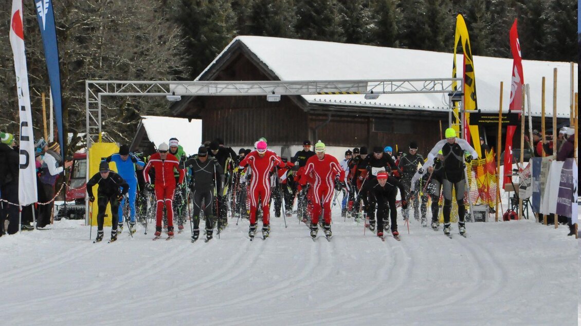Eine Gruppe von Skifahrern startet ein Rennen auf einer Schneepiste. Im Hintergrund sind Bäume und ein Gebäude zu sehen. | © Georg Petritsch