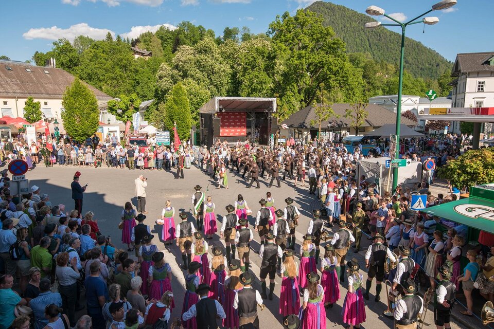 Eine lebendige Veranstaltung mit vielen Menschen, die sich um eine Bühne versammeln. Hinter der Menge sind grüne Berge zu sehen, die die Szenerie umrahmen. | © Narzissenfestverein