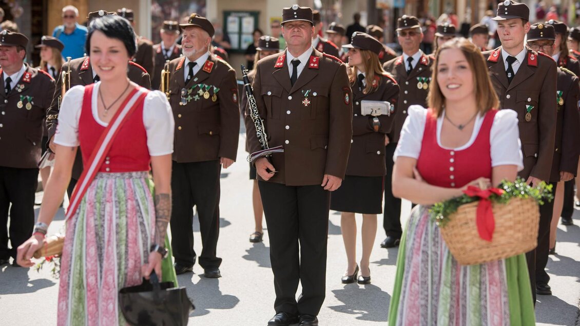 Eine traditionelle Parade mit Menschen in Trachten. Frauen tragen Dirndl und Männer Uniformen, während sie durch die Straße marschieren. | © Narzissenfestverein/St. Pelizzari