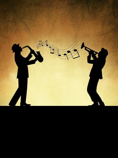 Two silhouettes of musicians playing saxophone and trumpet. Notes float above them against a warm, golden background. | © Pixabay