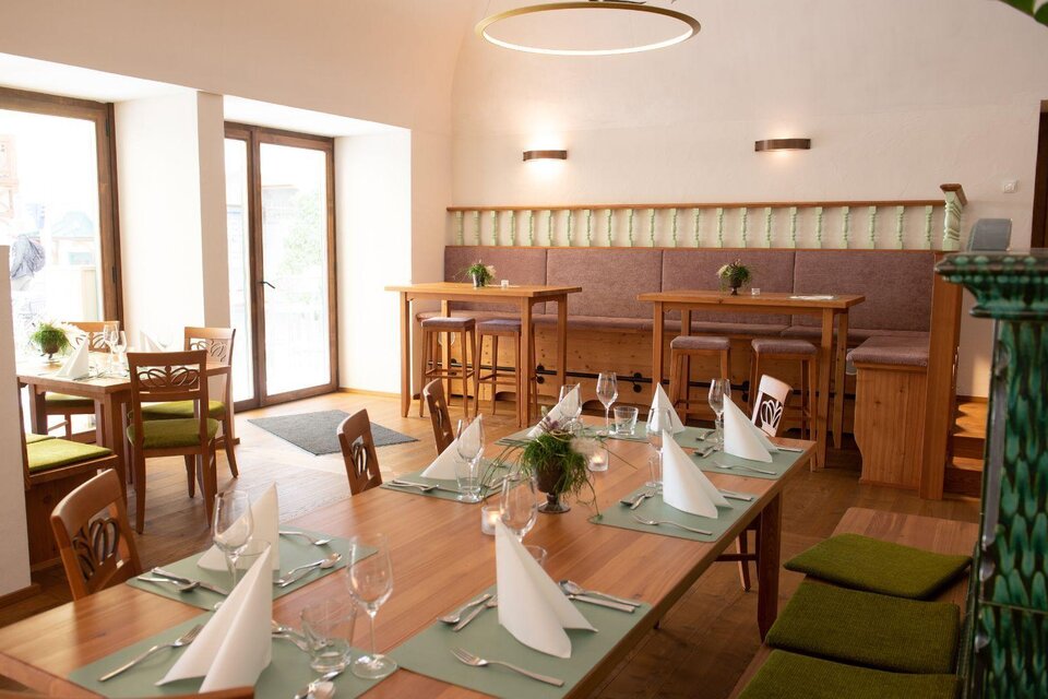 Ein modernes Restaurant mit Holz-Tischen und eleganter Tischdekoration. Die Atmosphäre ist hell und einladend, mit großen Fenstern und gemütlichen Sitzbereichen. | © Ralf Tornow