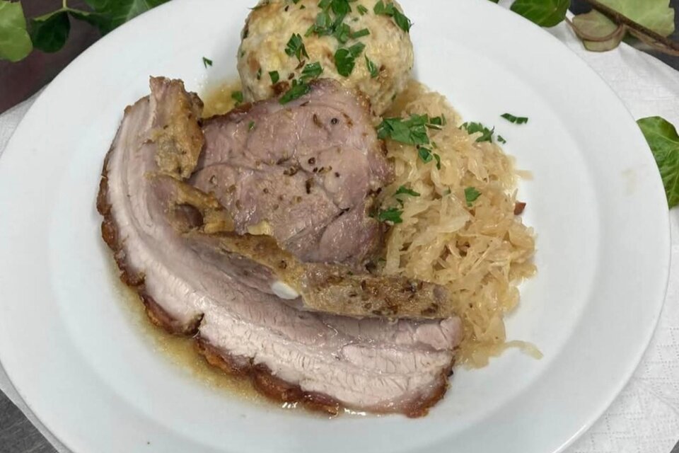 Ein Gericht mit saftigem Fleisch, Sauerkraut und Kartoffelknödeln. Alles ist mit frischer Petersilie garniert. | © Popp'n Angerl