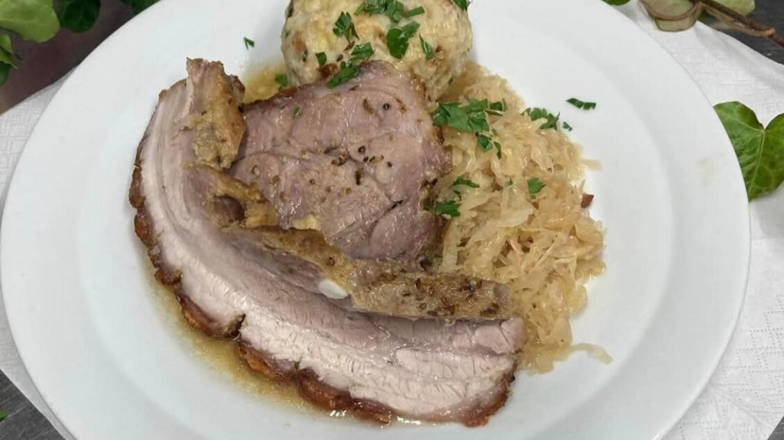 Ein Gericht mit saftigem Fleisch, Sauerkraut und Kartoffelknödeln. Alles ist mit frischer Petersilie garniert. | © Popp'n Angerl