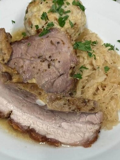 Ein Gericht mit saftigem Fleisch, Sauerkraut und Kartoffelknödeln. Alles ist mit frischer Petersilie garniert. | © Popp'n Angerl