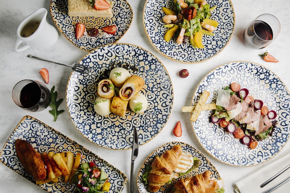 Ein bunter Teller mit Flaggen verschiedener Länder symbolisiert kulinarische Vielfalt. Der Slogan "Essen verbindet" vermittelt die Idee, dass Essen Menschen zusammenbringt.