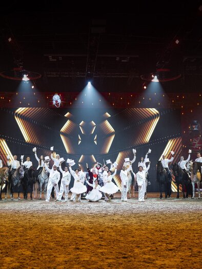 An impressive performance with horses and riders on a stage. The artists present synchronized movements under colorful lights. | © @CAVALLUNA