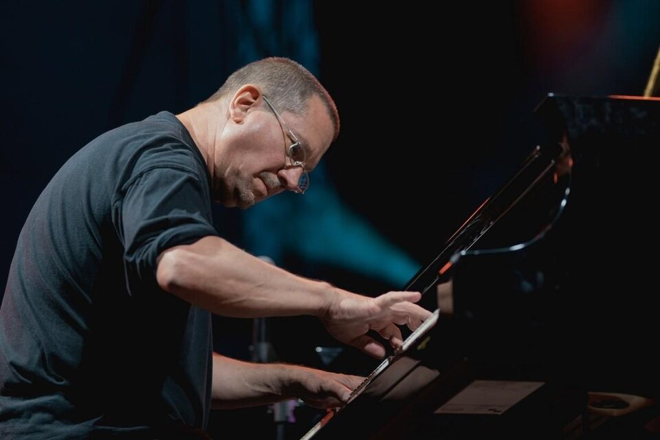 Ein Pianist spielt konzentriert am Klavier. Im Hintergrund sind verschwommene Lichter zu sehen. | © Tom Hejan