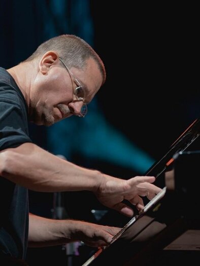A pianist is playing intently at the piano. Blurred lights can be seen in the background. | © Tom Hejan