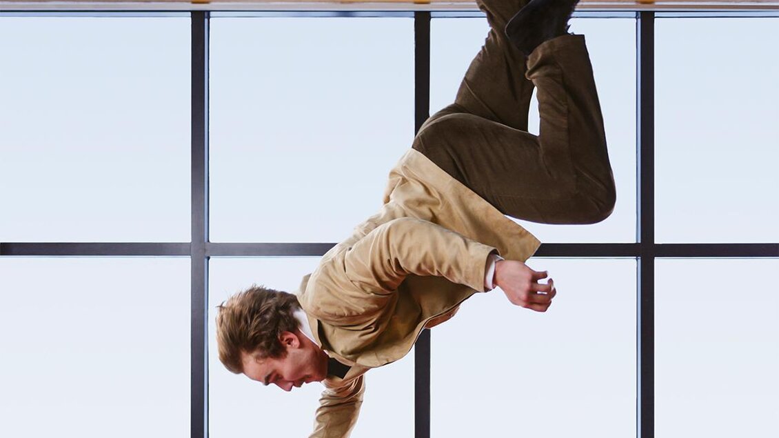Ein Artist greift von oben kommend nach einem Koffer in einer Vorstellung des Cirque Noël in Graz.  | © Emmanuel Burrie