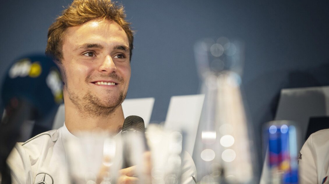 Ein junger Mann mit kurzen Haaren lächelt bei einer Pressekonferenz. Vor ihm stehen Wasserkrüge und ein Mikrofon. | © Red Bull Ring