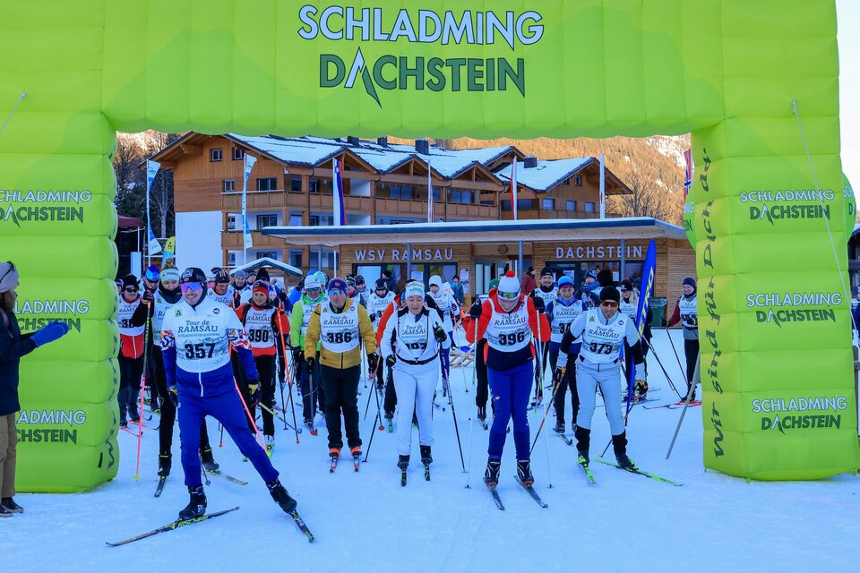 Ein Skirennen in Schladming-Dachstein mit vielen Teilnehmern. Sie stehen unter einem bunten Zielbogen auf Schnee. | © Michael Simonlehner