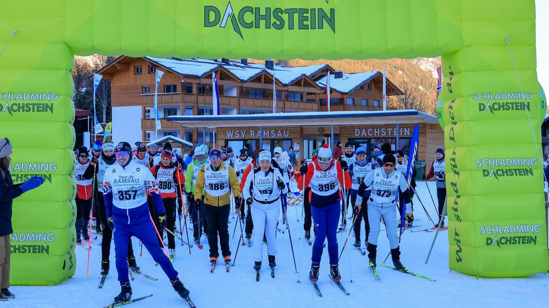 Ein Skirennen in Schladming-Dachstein mit vielen Teilnehmern. Sie stehen unter einem bunten Zielbogen auf Schnee. | © Michael Simonlehner