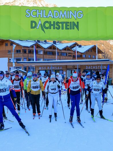 A ski race in Schladming-Dachstein with many participants. They are standing under a colorful finish arch on snow. | © Michael Simonlehner