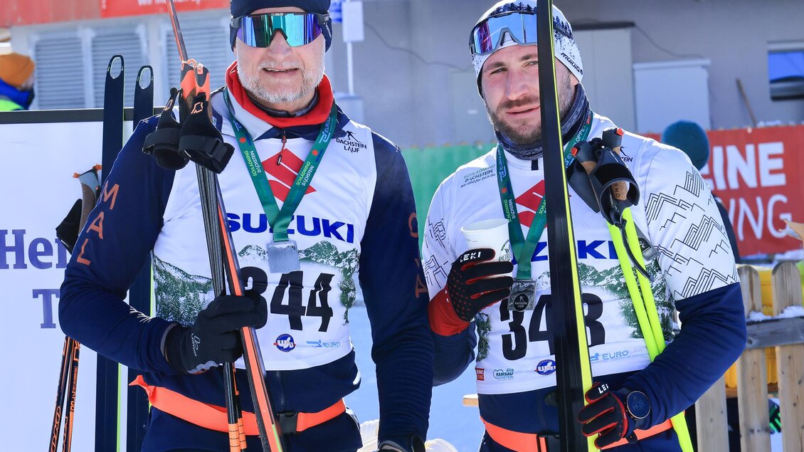 Zwei Männer stehen in Skibekleidung mit Skiern in der Hand. Sie tragen Medaillen und sehen bereit für einen Wettkampf aus. | © Michael Simonlehner
