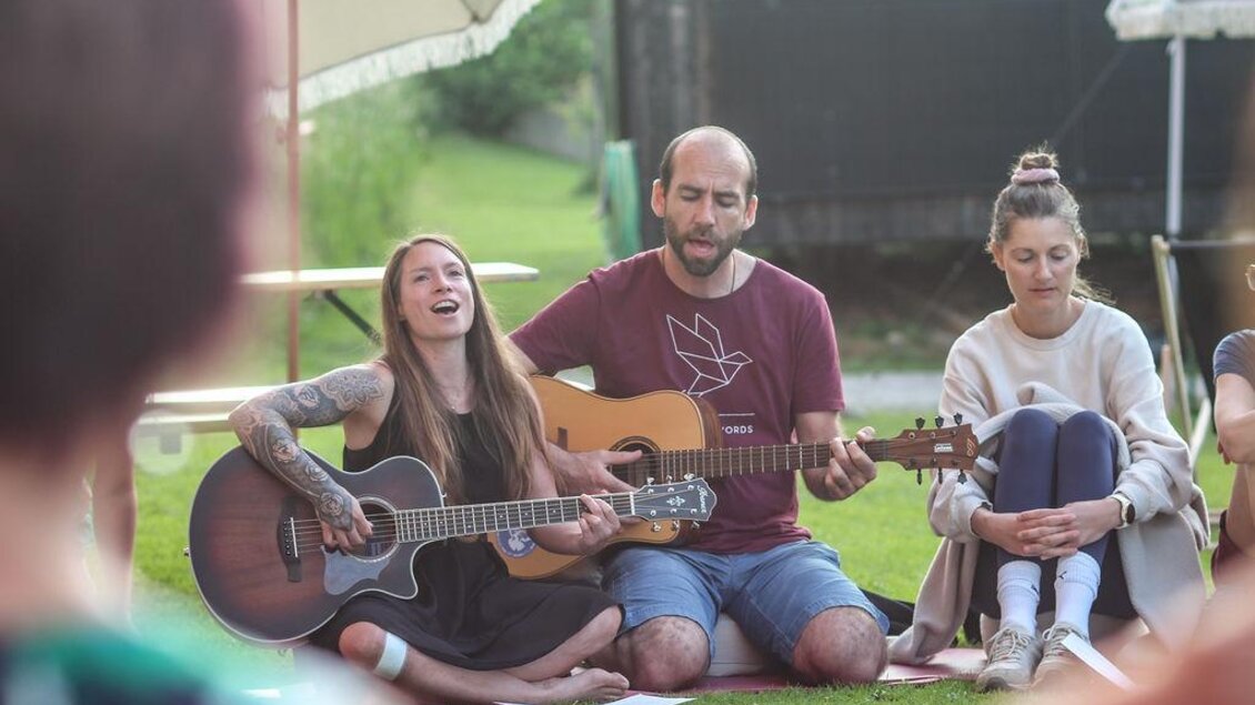 Mit Gitarre und Gesang wird im Kreis musiziert. Die Stimmung ist herzlich, getragen und verbindet alle Teilnehmer in einem gemeinsamen Moment. | © Das Bergyogafestival