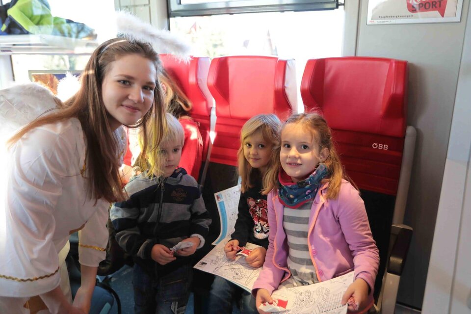 Ein fröhliches Kinderevent in einem Zug. Ein Mädchen im Engelkostüm steht neben drei Kindern, die mit Malutensilien beschäftigt sind. | © Andreas Kügerl