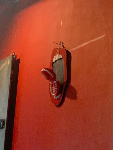 Ein rotes Wandbild mit einem Skateboard und einem Paar rote Flip-Flops. Der Hintergrund ist ebenfalls rot und sorgt für einen auffälligen Kontrast. | © Lena Pöltl.