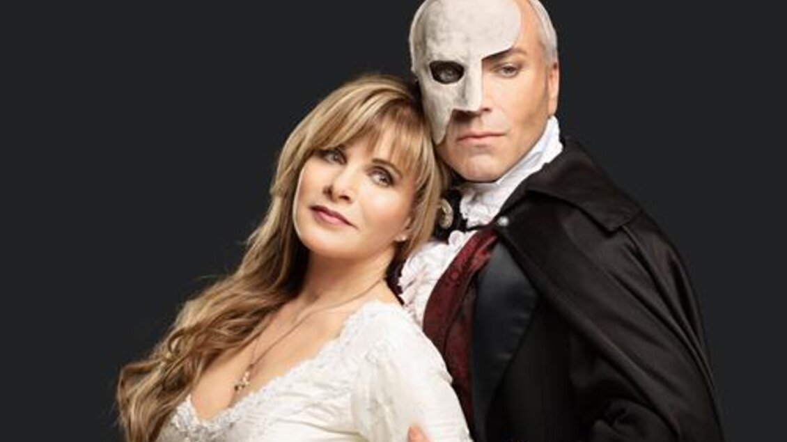 Ein Paar in historischer Kostümierung, bestehend aus einer Frau in einem eleganten weißen Kleid und einem Mann mit einer Maske. Der Hintergrund ist schwarz, was den Fokus auf die Charaktere lenkt.