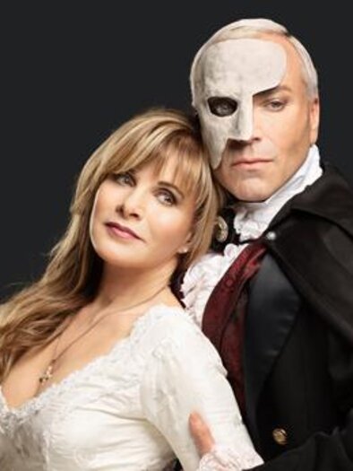 A couple in historical costume, consisting of a woman in an elegant white dress and a man with a mask. The background is black, which draws the focus to the characters.
