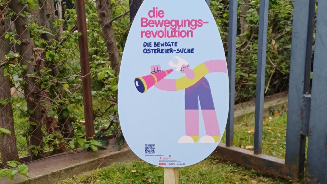 Ein Schild steht im Freien, umgeben von Gras und Gehwegplatten. Es enthält farbenfrohe Grafiken und Text zu einer Veranstaltung oder Information. | © Oststeiermark Tourismus