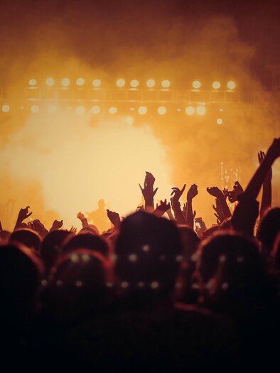 A crowd at a concert with raised hands. Bright lights shine in the background, creating an exciting atmosphere. | © Pixabay