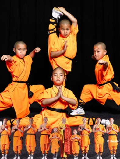 Four children in orange martial arts clothing are demonstrating impressive martial arts poses. The background is black, which highlights the movements and the clothing.